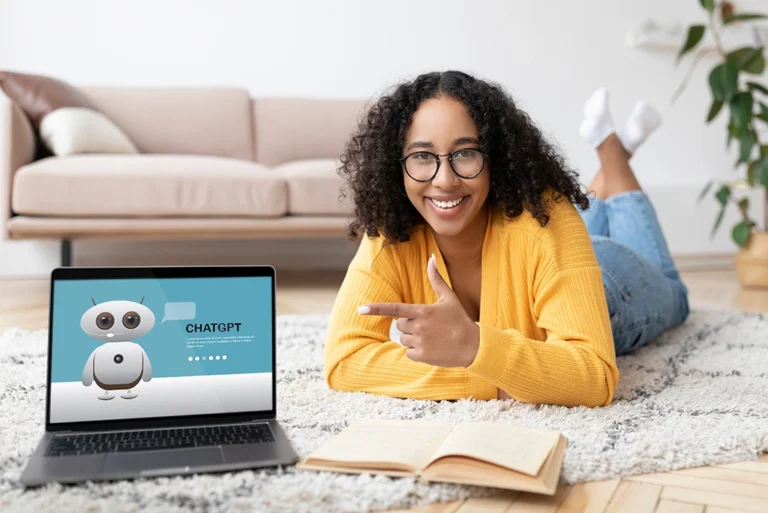 Mujer sonriendo y señalando una laptop y usando ChatGPT para estudiar.