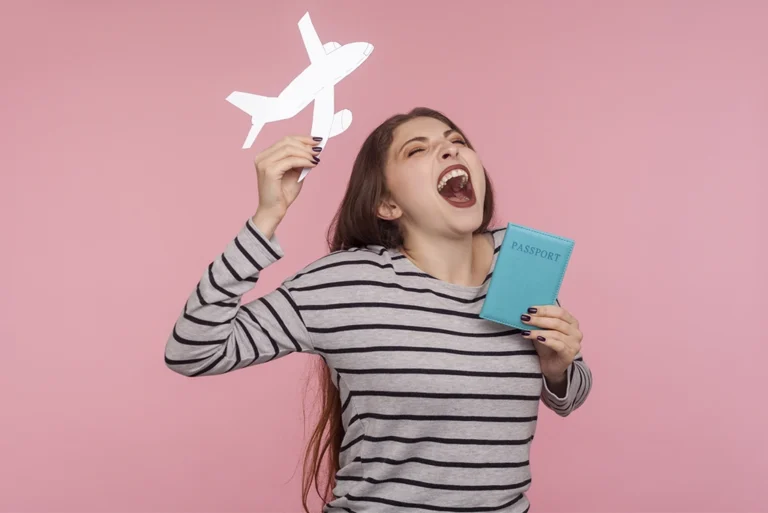 Joven emocionada con su pasaporte y un avión de papel, simbolizando los trámites a los 18 años para viajar y alcanzar nuevas metas.