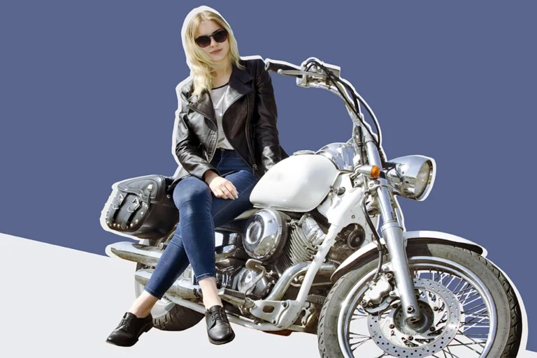 Joven sentada en una motocicleta blanca, usando una chaqueta de cuero y gafas de sol, lista para iniciar su viaje con estilo. Perfecta para quienes buscan consejos clave antes de comprar su primera moto.