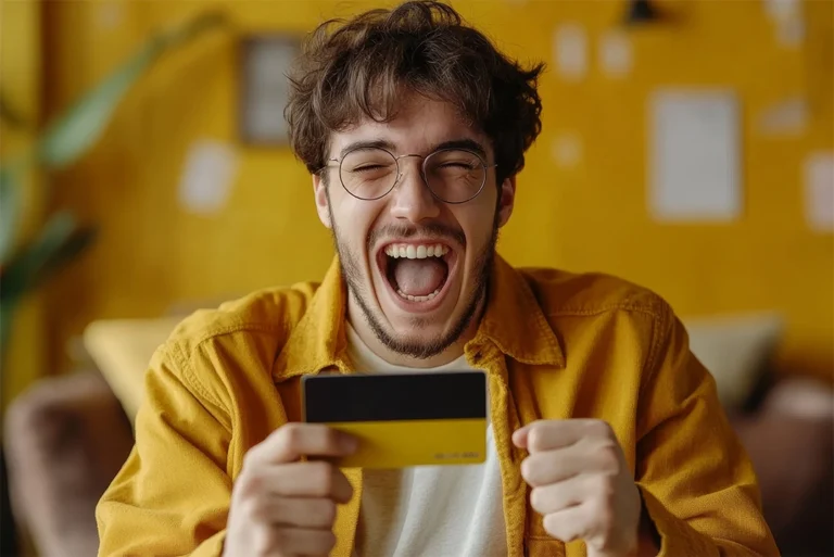 Joven feliz celebrando la obtención de su primera tarjeta bancaria.