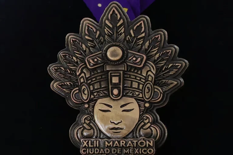 Medalla Maratón de la CDMX 2025 inspirada en Cihuacóatl, diosa mexica mujer serpiente, sobre fondo de textura prehispánica.