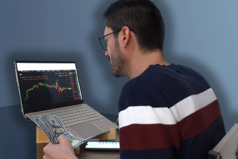 Joven universitario sonriente frente a una laptop, viendo gráficos de crecimiento financiero en la pantalla durante la Semana Nacional de Educación Financiera, promocionando cursos de educación financiera gratuitos