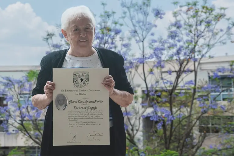 Retrato de Marta Elena Guerra Treviño, la mujer más longeva en obtener doctorado en la UNAM a los 89 años, sosteniendo su título doctoral en la Facultad de Filosofía y Letras, rodeada de libros y con una sonrisa de orgullo.