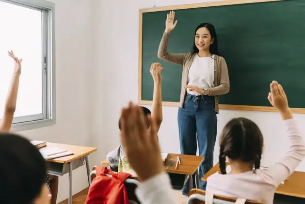 Docente sonriente usando laptop para revisar la convocatoria SEP en línea de Licenciatura en Educación Primaria