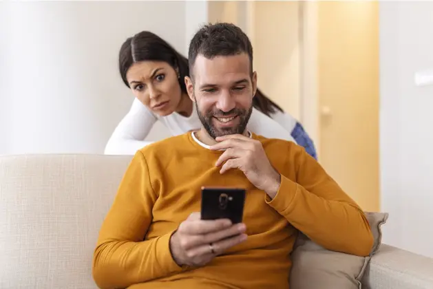 Joven con expresión preocupada mirando fijamente la pantalla de un teléfono móvil, representando la ansiedad y los celos patológicos del síndrome de Otelo