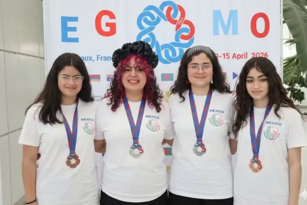 Cuatro jóvenes estudiantes mexicanas posan con sus medallas de plata y bronce después de su participación en la olimpiada femenil de matemáticas realizada en Burdeos, Francia, vistiendo playeras blancas con el logo de México.